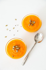 Two plates of pumpkin soup with seeds on a white background with space for your text.