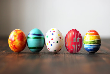Fototapeta na wymiar Easter colorful eggs on wooden background with egg shaped words Happy Easter.