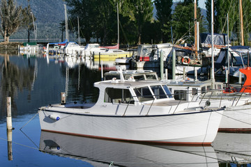 Leisure craft moored in a lakeside boating marina in directional morning sunlight and calm water.