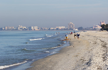 St. Pete Beach, Florida, January 2017: People walking in the surf on St. Pete Beach, Florida looking for shells on a sunny day after a strong wind storm at St. Pete Beach, Florida.