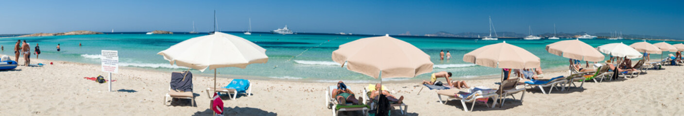 Fototapeta na wymiar FORMENTERA, SPAIN - JUNE 2015: Tourists enjoy beautiful Illetes Beach. Formentera is a famous destination for young people in Europe