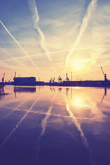 Sunrise over crane silhouettes in Szczecin (Stettin) harbor, color toning applied, Poland.