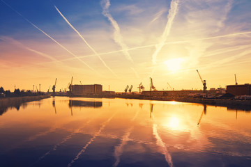 Sunrise over crane silhouettes in Szczecin harbor, Poland. - obrazy, fototapety, plakaty