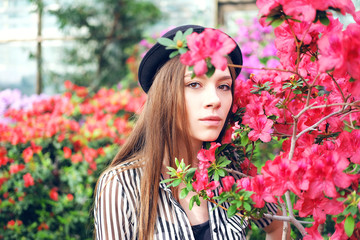 Tender sweet young woman enjoying azalea flowers in greenhouse