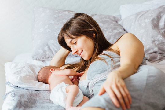 Mother with newborn baby lying on the bed at home. Motherhood concept