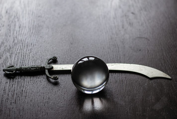 Crystal fortune-telling ball with dagger placed on table