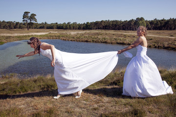 just married happy lesbian couple in white dress has fun near small lake
