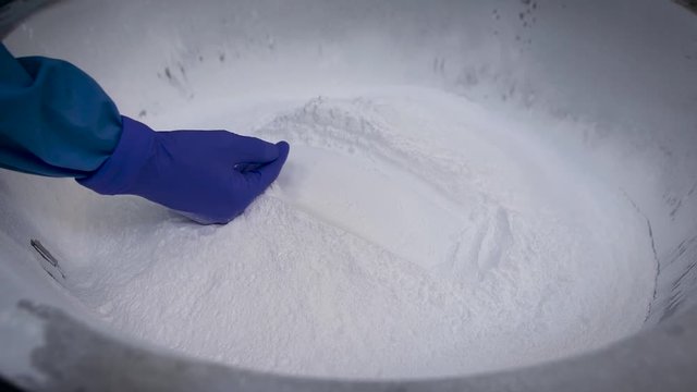 Underground narcotic laboratory. A man in a protective suit is engaged with a wholesale party of heroin or cocaine. A huge amount of white powder