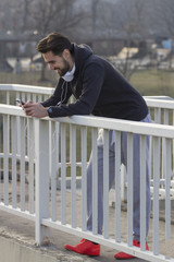 Jogger leaning on the fence with mobile phone on his hand