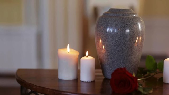funerary urn and candles on table burning indoors