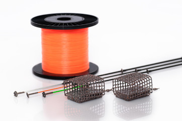 Feeder baskets next to feeder rod tips and orange monofilament fishing line spool