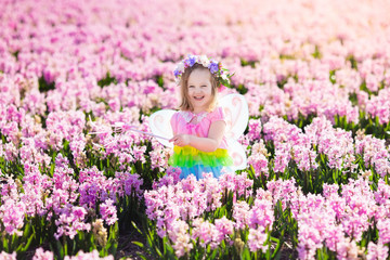 Little girl in fairy costume playing in flower field