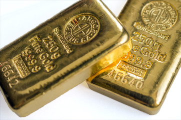 Two cast gold bars on a white background. Selective focus.