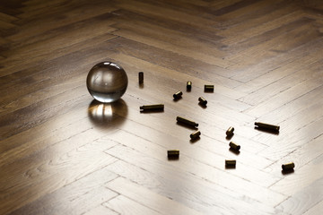 Crystal fortune-telling ball with ammo placed on wooden floor