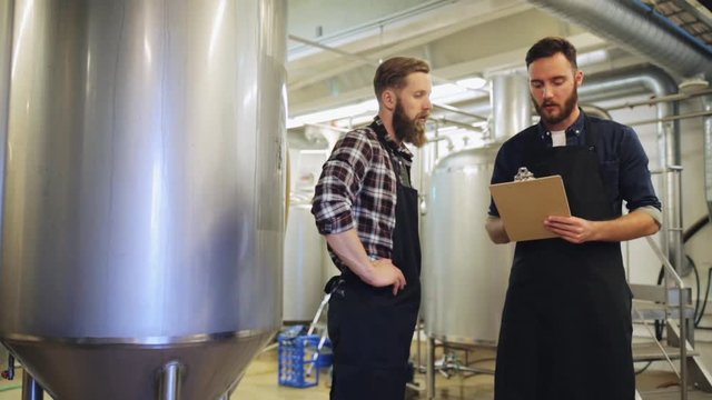 men with clipboard at brewery or beer plant