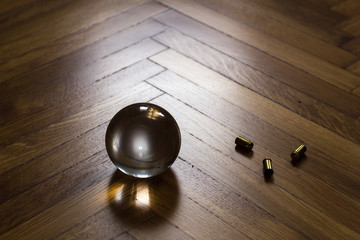 Crystal fortune-telling ball with ammo placed on wooden floor