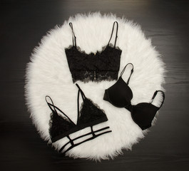 Fashion concept, three lace bustier on a white fur, top view