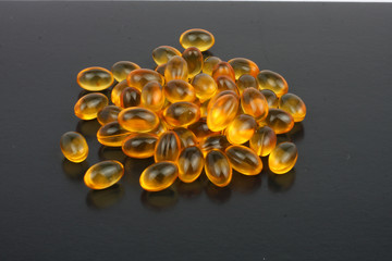 fish oil capsules on black background