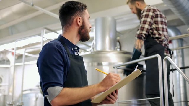 men with clipboard at brewery or beer plant