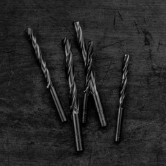 Set of drill bits on wooden background. Symbolic repair tool, black and white