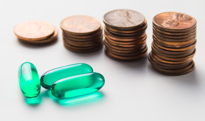 3 green capsule drugs on white background with soft focus stack of 1 Cent coin