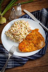 Fried pork chop in breadcrumbs, served with vegetable salad.