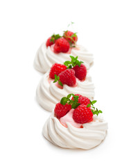 Mini  Pavlova meringue nests with berries and mint on isolated on white