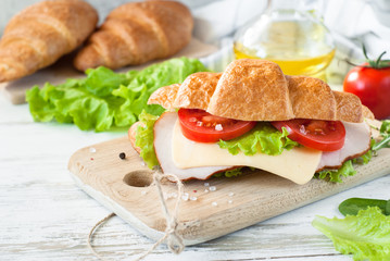 Croissant sandwich with bacon, cheese, lettuce and tomato