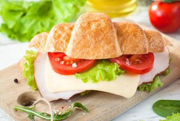 Croissant sandwich with bacon, cheese, lettuce and tomato