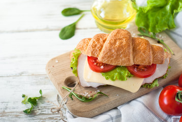Croissant sandwich with bacon, cheese, lettuce and tomato