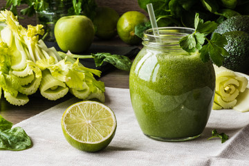Detox diet. Green smoothie with different vegetables on wooden background