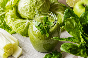 Detox diet. Green smoothie with different vegetables on wooden background
