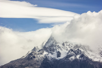mountains of patagonia in haze at daylight with windy lenticular clouds