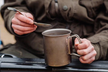 hunter holding titanium mug in a winter forest. Bushcraft, hunting and people concept