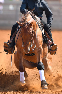 A front view of a rider sliding the horse in the dirt