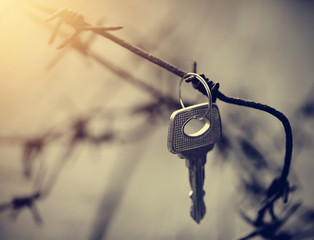 Key hangs on a rusty barbed wire.