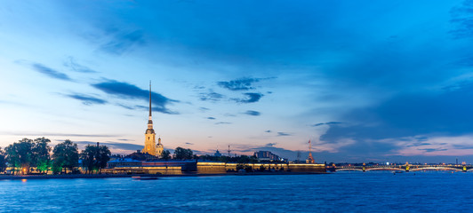Obraz premium Peter and Paul fortress with the Palace promenade at sunset on a background of pure pink sky with reflection in the water of the Neva river during the white nights in St. Petersburg