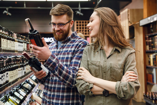 Young  Couple Choosing Bottle Of Wine