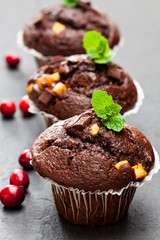 Triple  chocolate muffins with cranberries on black stone background