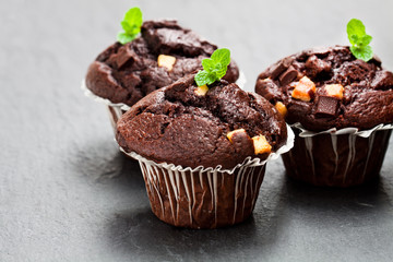 Triple  chocolate muffins on black stone background