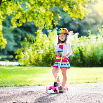Kids riding scooter in summer park.
