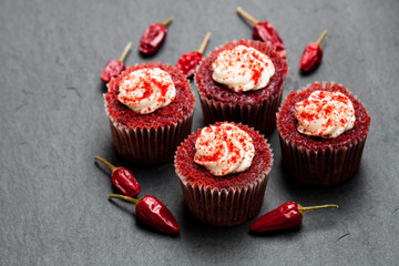 Chocolate  cupcakes with red hot chili pepper on black stone background