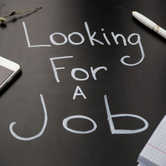 I'm looking for a job. An inscription on a black board. On the table next to gadgets and a notebook with a pen