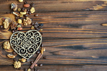 Delicate laced wooden heart with healthy ingredients like raisins, nuts and cinnamon on natural wooden background with copy space for your text