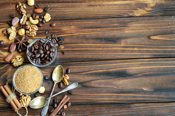 Small glass bowls with cane brown sugar and coffee beans with healthy ingredients like raisins, nuts and cinnamon on natural wooden background with copy space for your text