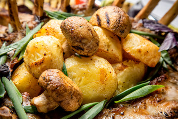 Grilled potatoes and mushrroms with meat and herbs close up
