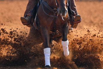 A front view of a rider sliding the horse in the dirt
