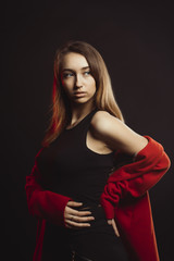 Fashionable young woman in red coat at studio