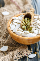 Wooden scoop in bowl with pumpkin seeds.