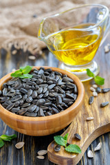 Wooden bowl with sunflower seeds and oil in glass cup.